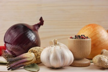 Spices on the wooden board. Horseradish root, red and yellow onions, garlic and multi colored...
