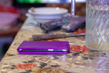 mobile phone is on the table next to a jug of water and plates