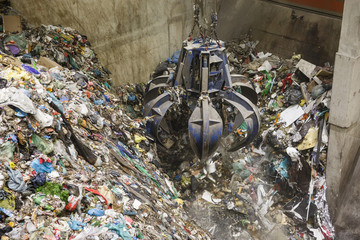 Mechanical claw hand grabbing pile of mixed waste