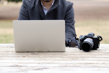 屋外でパソコンを操作する男性カメラマン