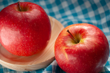 Two red apples on blue and white checkered cloth. Close-up focused.