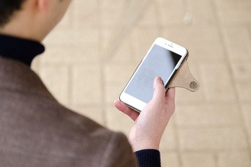 屋外でスマホを操作するジャケットを着た男性