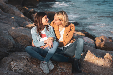 Young teenage girl with her mother in affectionate gesture by the sea. Family vacations on the coast