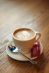 una taza de café con leche y azúcar sobre una mesa de madera en un bar