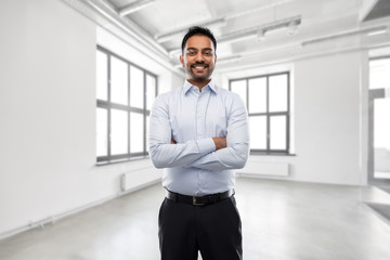 business, realty and people concept - smiling indian businessman or realtor over empty office room background