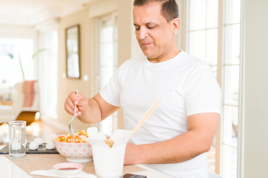 Middle age man eating asian food at home