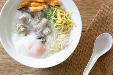 Rice congee delicious asian breakfast food in white bowl and spoon on brown napery