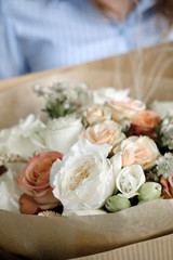 Bouquet of white and beige Roses. Woman Florist holding bouquet of Flowers indoor. Female florist preparing bouquet in flower shop. Close up. Mother's Day and Valentine's Day concept
