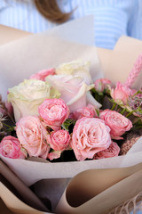 Bouquet of white and pink Roses. Woman Florist holding bouquet of Flowers indoor. Female florist preparing bouquet in flower shop. Close up. Copy space. Mother's Day and Valentine's Day concept