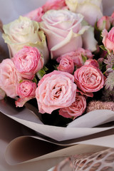 Bouquet of white and pink Roses. Woman Florist holding bouquet of Flowers indoor. Female florist preparing bouquet in flower shop. Close up. Copy space. Mother's Day and Valentine's Day concept
