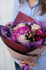 pink and purple bouquet of roses. woman florist holding bouquet of flowers indoor. Female florist preparing bouquet  in flower shop. Close up. Mother's Day and Valentine's Day concept