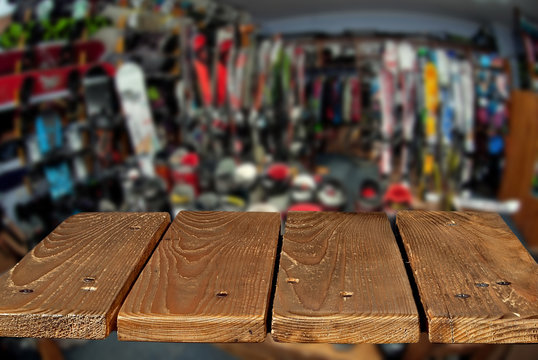 Mockup. Image of sport store with equipment for skiing. Defocused, blurred image. In the foreground is the top of a wooden table, counter.
