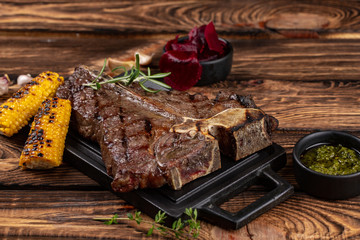 Medium rare grilled Steak Ribeye Black Angus with corn and rosemary on serving on wooden background