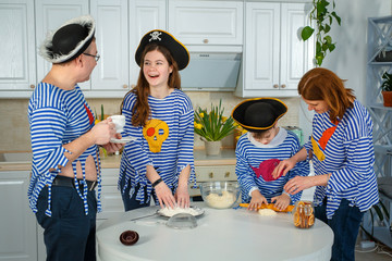 Photo session - friendly family. The family cooks together. Husband, wife and their children in the kitchen. Family kneads dough with flour. Prepare the dough in the kitchen.