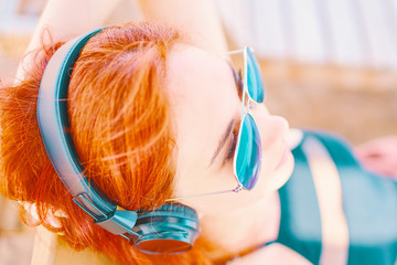 Woman in sunglasses listening to music on beach.