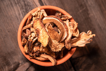 Dried wild boletus mushrooms in vintage ceramic bowl on old wooden table