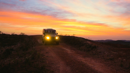 Car off road 4x4 exploring forests and national parks, day starting and sun rising on the horizon