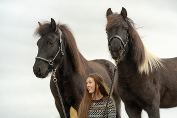 Happy Swedish girl with long brown hair with her two Icelandic horses