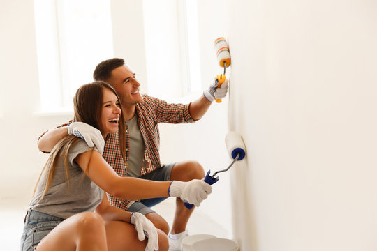 Happy Couple Painting a Wall with a Paint Roller