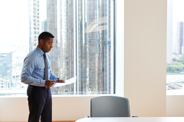 Mature Businessman Standing Rehearsing Before Giving Presentation In Modern Open Plan Office