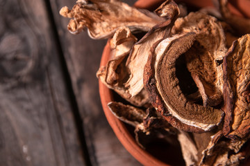 Dried wild boletus mushrooms in vintage ceramic bowl on old wooden table