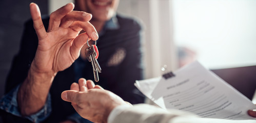 Real estate agent passing keys to his client - obrazy, fototapety, plakaty