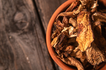 Dried wild boletus mushrooms in vintage ceramic bowl on old wooden table