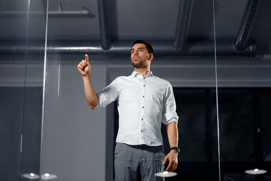 Business, Technology And People Concept - Businessman Working And Touching Glass Wall At Night Office