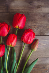 Row of red tulips on wooden background with space for message. Mother's Day background. Top view.
