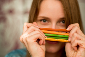 Close-up portrait of a beautiful excited woman with color pencils 