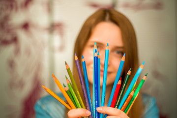 Close-up portrait of a beautiful excited woman with color pencils 
