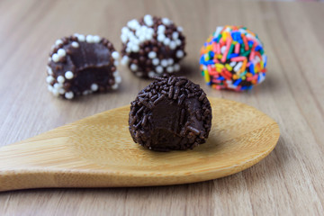 brigadeiro (brigadier), sweet chocolate typical of Brazilian cuisine covered with particles, in a wooden background.