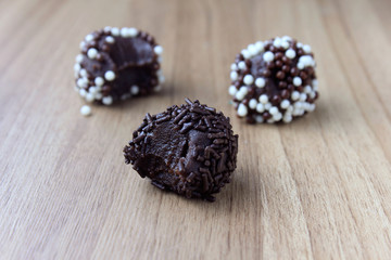brigadeiro (brigadier), sweet chocolate typical of Brazilian cuisine covered with particles, in a wooden background.