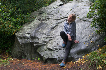 Girl teenager depressed on the background of a large stone.