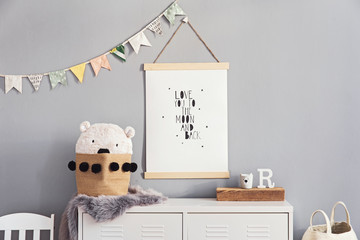 Stylish and cute scandinavian decor of  kid room with mock up poster, white shelf, natural toys, hanging decor flags , child's armchair, basket for accessories and teddy bears. Minimalistic concept.