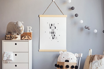The modern scandinavian newborn baby room interior with mock up poster , white furnitures, natural toys, hanging cotton lamps and teddy bear. Minimalistic and cozy interior with grey walls. 