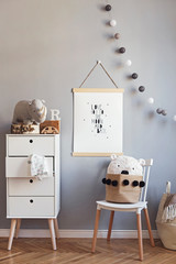 Scandinavian child room with mock up poster frame on the grey wall, white commode, teddy bear and...