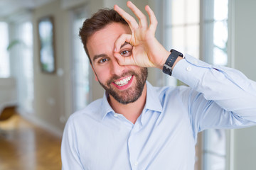 Obraz premium Handsome business man doing ok gesture with hand smiling, eye looking through fingers with happy face.