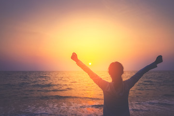 Fototapeta premium Copy space of woman rise hand up on sunset sky at beach and island background.