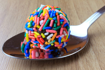 brigadeiro (brigadier), sweet chocolate typical of Brazilian cuisine covered with particles, in a wooden background.