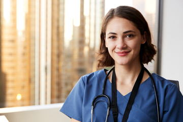 Portrait Of Smiling Female Doctor Wearing Scrubs With Stethoscope In Hospital Office