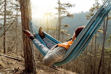 Young happy man relaxing lying in hammock on top of mountain. - 251575075