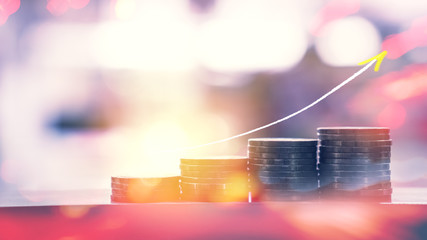 Stack of coin row on table double exposure with up trend graph and blur colorful bokeh sun light abstract background.