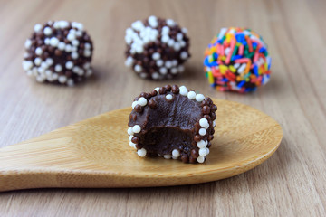 brigadeiro (brigadier), sweet chocolate typical of Brazilian cuisine covered with particles, in a wooden background.
