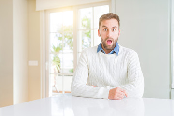Naklejka premium Handsome man wearing casual sweater afraid and shocked with surprise expression, fear and excited face.