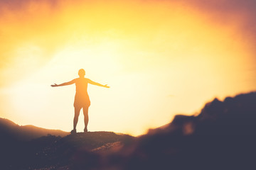 Copy space of woman rise hand up on top of mountain and sunset sky abstract background.