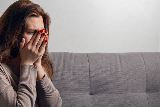 The young woman is crying. Tears flow down her cheeks.