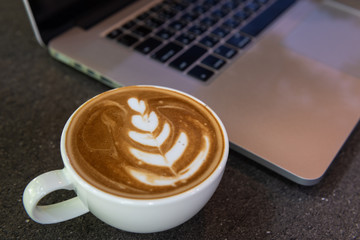Latte art coffee cup with laptop computer