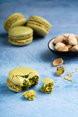 Macarons mit Pistazien zerbrochen mit fokus im vordergrund und weiteren Macarons und Pistazien im...