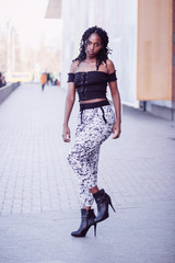 Young woman dressed in casual clothes walking on the street, soft focus background